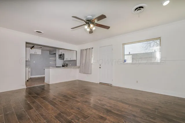 a view of a livingroom with a ceiling fan wooden floor and a ceiling fan