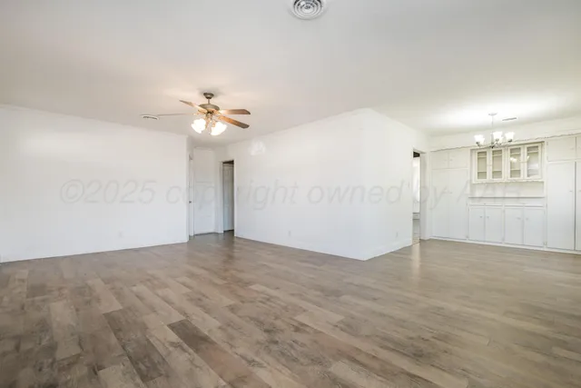 wooden floor in an empty room with a chandelier fan