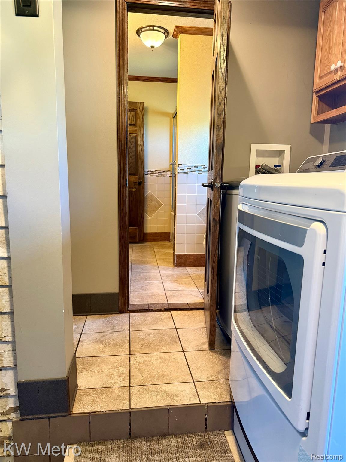 5982 South Mission Road Mount Pleasant, MI 48858 - Photo 8 of 32 Laundry room featuring washer / clothes dryer, light tile patterned floors, crown molding, and cabinet space