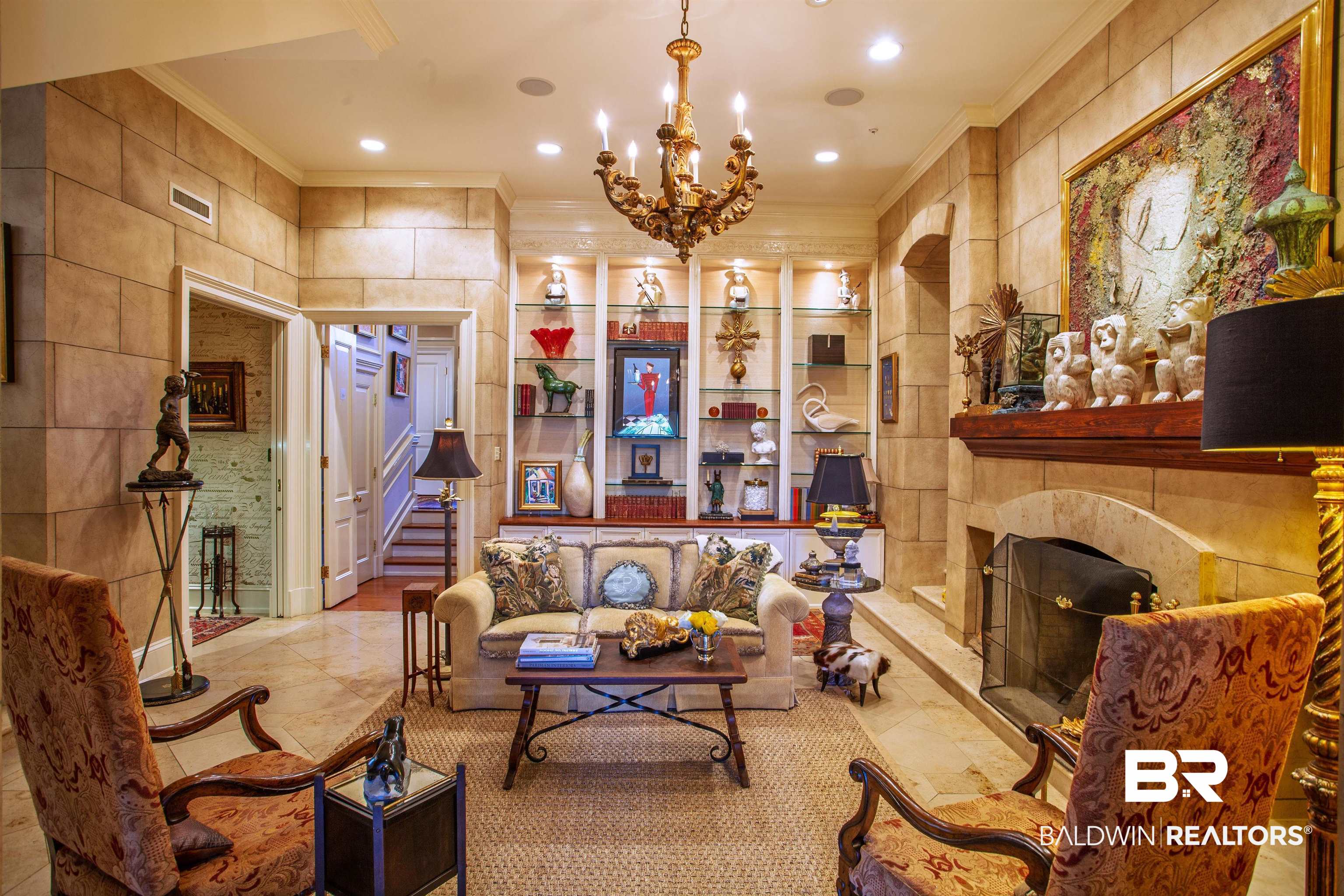 150 Austill Avenue Mobile, AL 36608 - Photo 19 of 39 Living area featuring stone-finish walls, a built-in fireplace with a stone surround, and an ornate chandelier