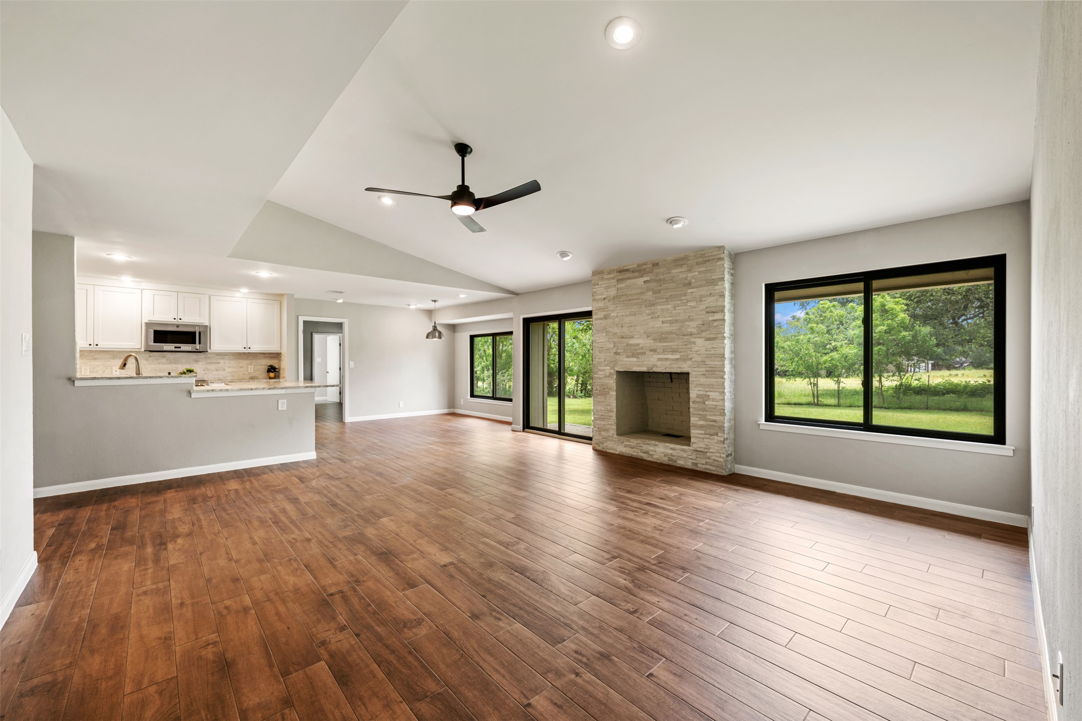 1600 Pin Oak Lane Round Rock, TX 78681 - Photo 12 of 40 Spacious interior with wood-finish flooring, a stone-clad fireplace, and multiple windows