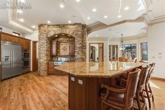 a kitchen with stainless steel appliances granite countertop a kitchen island a stove a sink a dining table and chairs