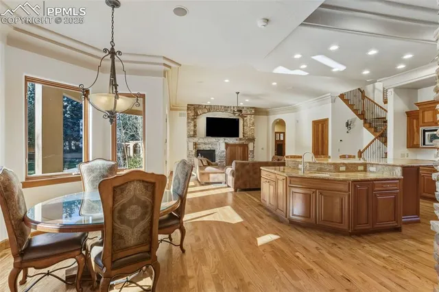 a view of kitchen with stainless steel appliances granite countertop a stove top oven a sink dishwasher a dining table and chairs with wooden floor