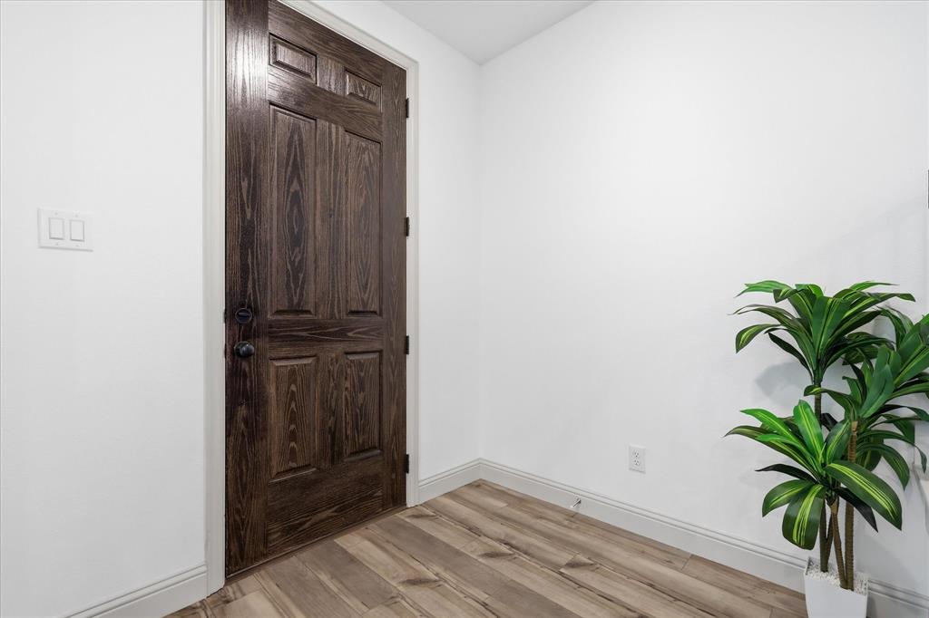 Paneled wood-finish door with dark hardware, set against crisp white walls