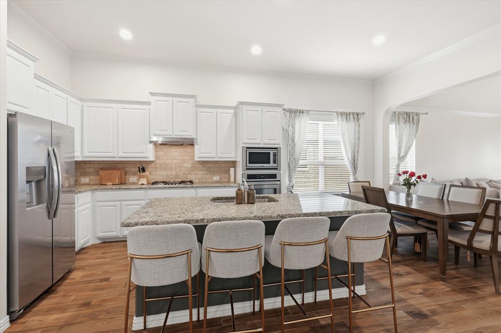 215 Equestrian Road Hickory Creek, TX 75065 - Photo 10 of 36 a kitchen with granite countertop a dining table chairs and refrigerator