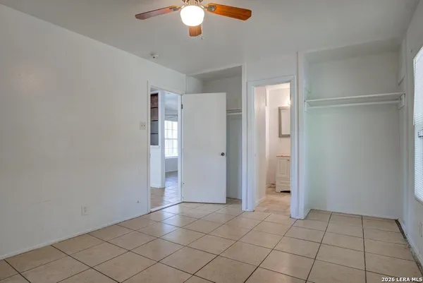 an empty room with closet and a chandelier fan