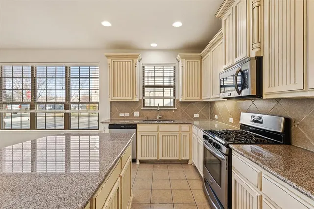 a kitchen with stainless steel appliances granite countertop a stove a sink and a microwave