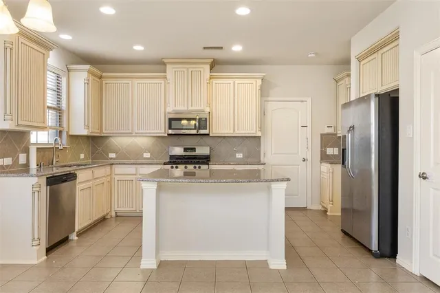 a kitchen with stainless steel appliances granite countertop a refrigerator and a stove top oven