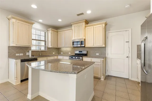 a kitchen with stainless steel appliances granite countertop a stove a sink and a refrigerator with wooden cabinets