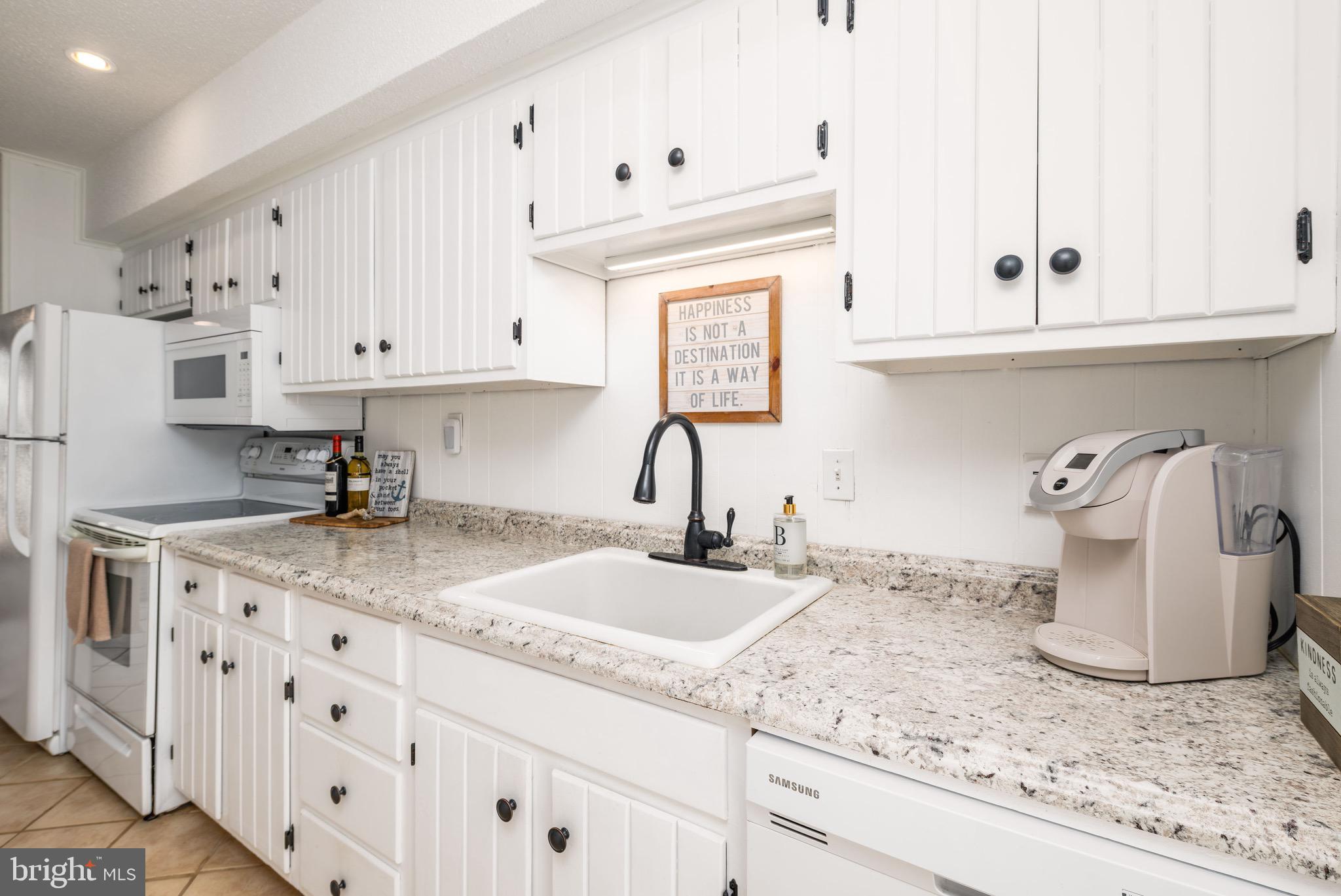 720 Rusty Anchor Road, Unit 41C Ocean City, MD 21842 - Photo 6 of 32 a kitchen with granite countertop white cabinets and white appliances