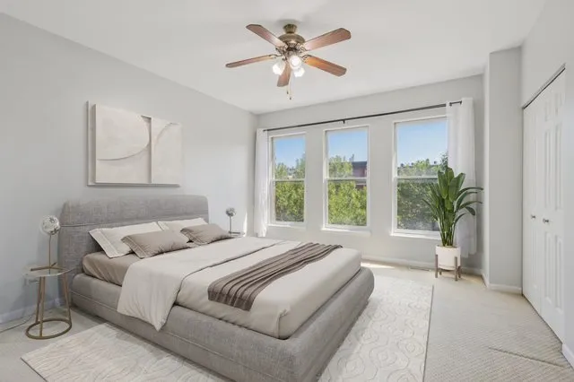 a bedroom with a large bed and a chandelier fan