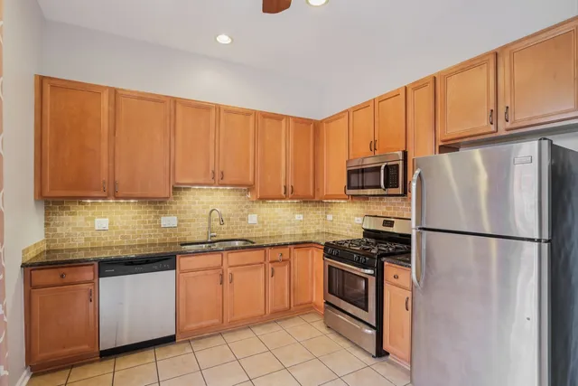 a kitchen with stainless steel appliances granite countertop a refrigerator sink stove microwave and cabinets