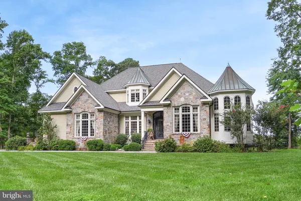 a front view of a house with a garden and trees