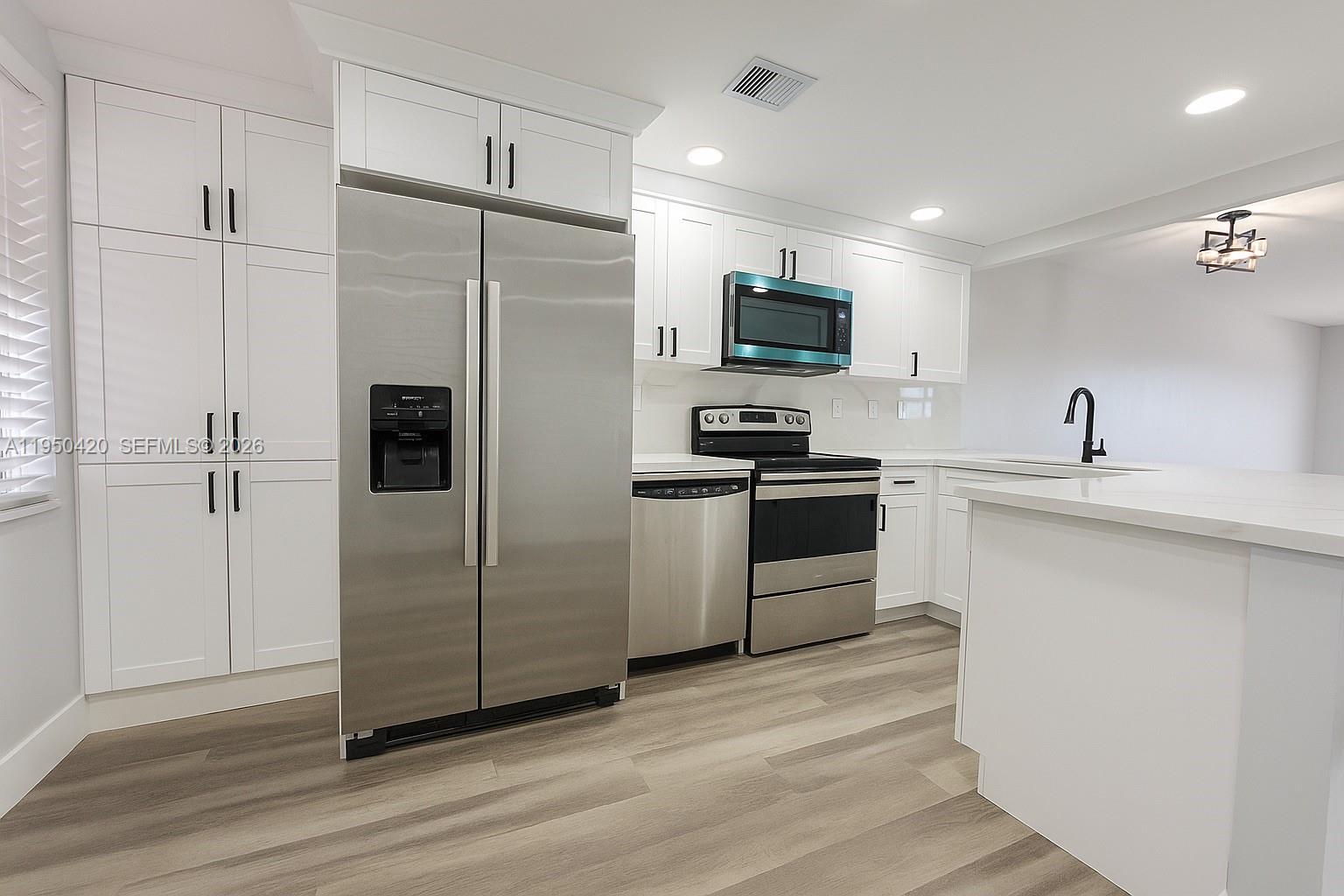 a kitchen with stainless steel appliances a refrigerator sink and microwave