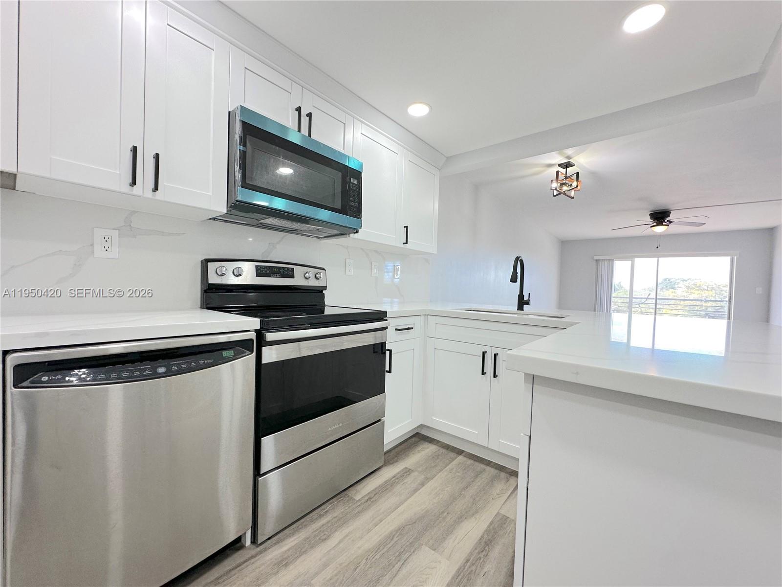 3110 North Pine Island Road, Unit 408 Sunrise, FL 33351 - Photo 2 of 18 a kitchen with stainless steel appliances a stove microwave and sink