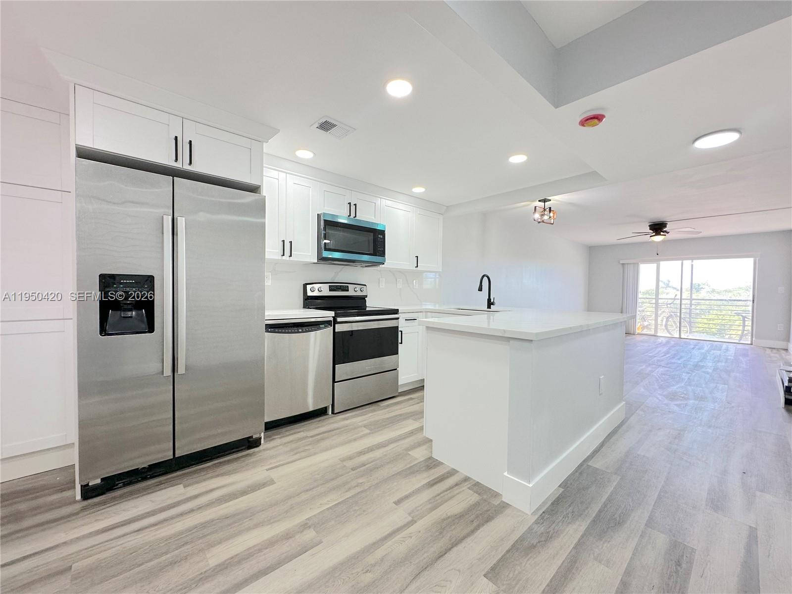 3110 North Pine Island Road, Unit 408 Sunrise, FL 33351 - Photo 5 of 18 a kitchen with stainless steel appliances kitchen island granite countertop a stove a sink and a refrigerator