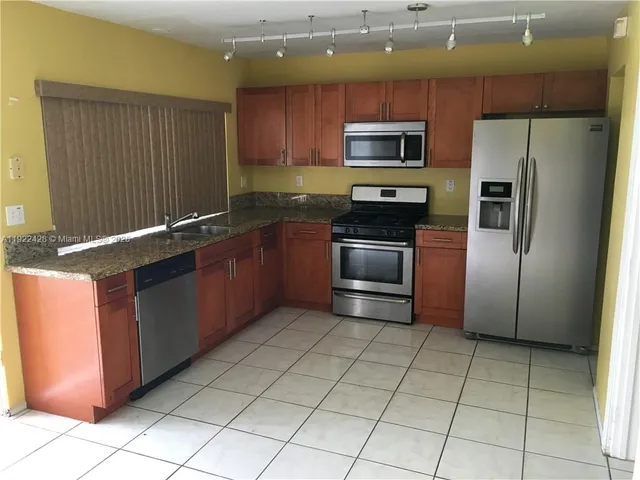 a kitchen with stainless steel appliances granite countertop a refrigerator and a stove top oven
