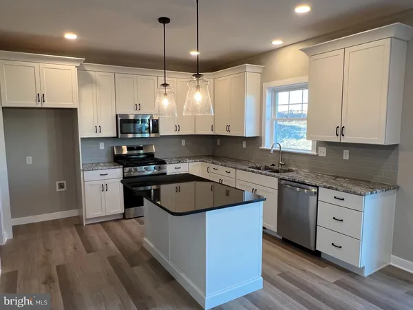 a kitchen with granite countertop a refrigerator a sink and dishwasher a stove top oven with wooden floor