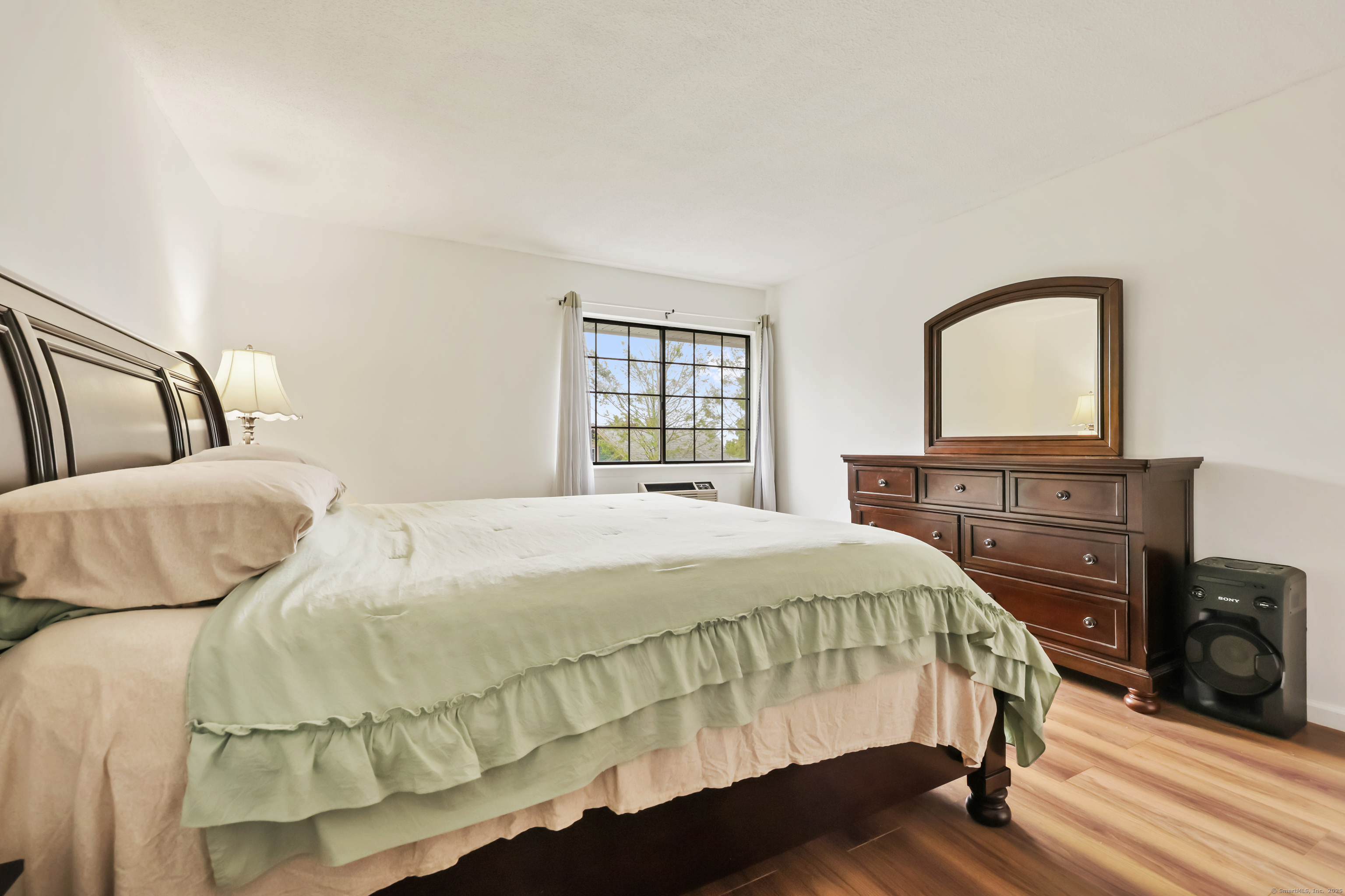 187 Flax Hill Road, Unit D5 Norwalk, CT 06854 - Photo 16 of 19 a bedroom with a bed a dresser and a window