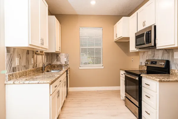 a kitchen with stainless steel appliances granite countertop a sink stove and microwave