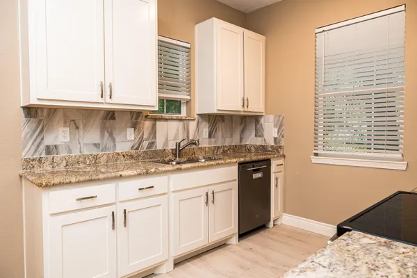 a kitchen with granite countertop white cabinets and a window