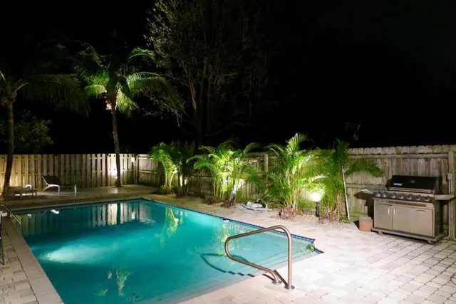 a porch with a table and chairs a barbeque with potted plants