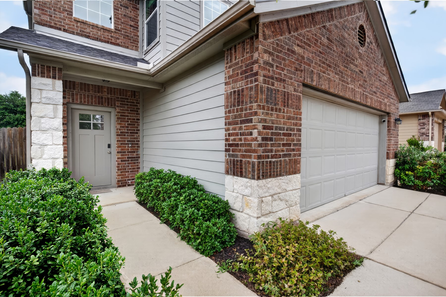 2006 Grow Lane Austin, TX 78754 - Photo 3 of 40 A welcoming brick and stone facade with a modern garage door and well-maintained shrubbery offers inviting curb appeal.