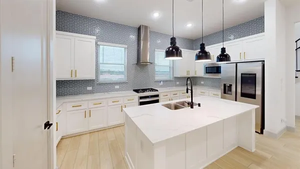 a kitchen with stainless steel appliances a sink a stove a refrigerator and cabinets