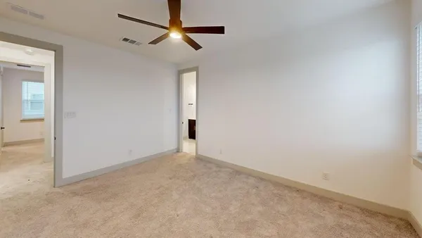 an empty room with a ceiling fan and carpet