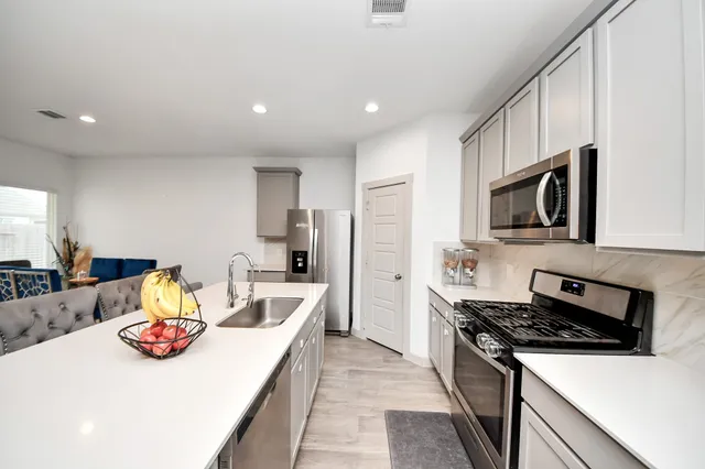 a kitchen with stainless steel appliances a stove a sink a microwave a refrigerator and cabinets