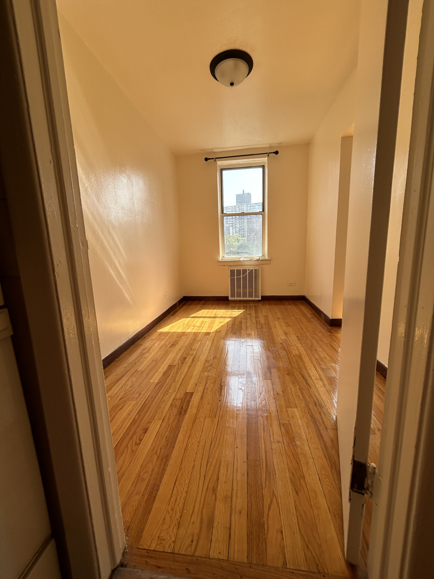 2385 Barker Avenue, Unit 5L Bronx, NY 10467 - Photo 9 of 15 a view of a room with wooden floor and a window