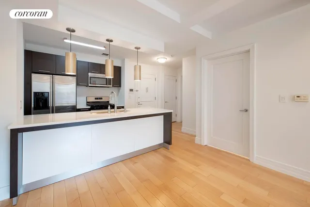 a large white kitchen with kitchen island a sink stainless steel appliances and cabinets