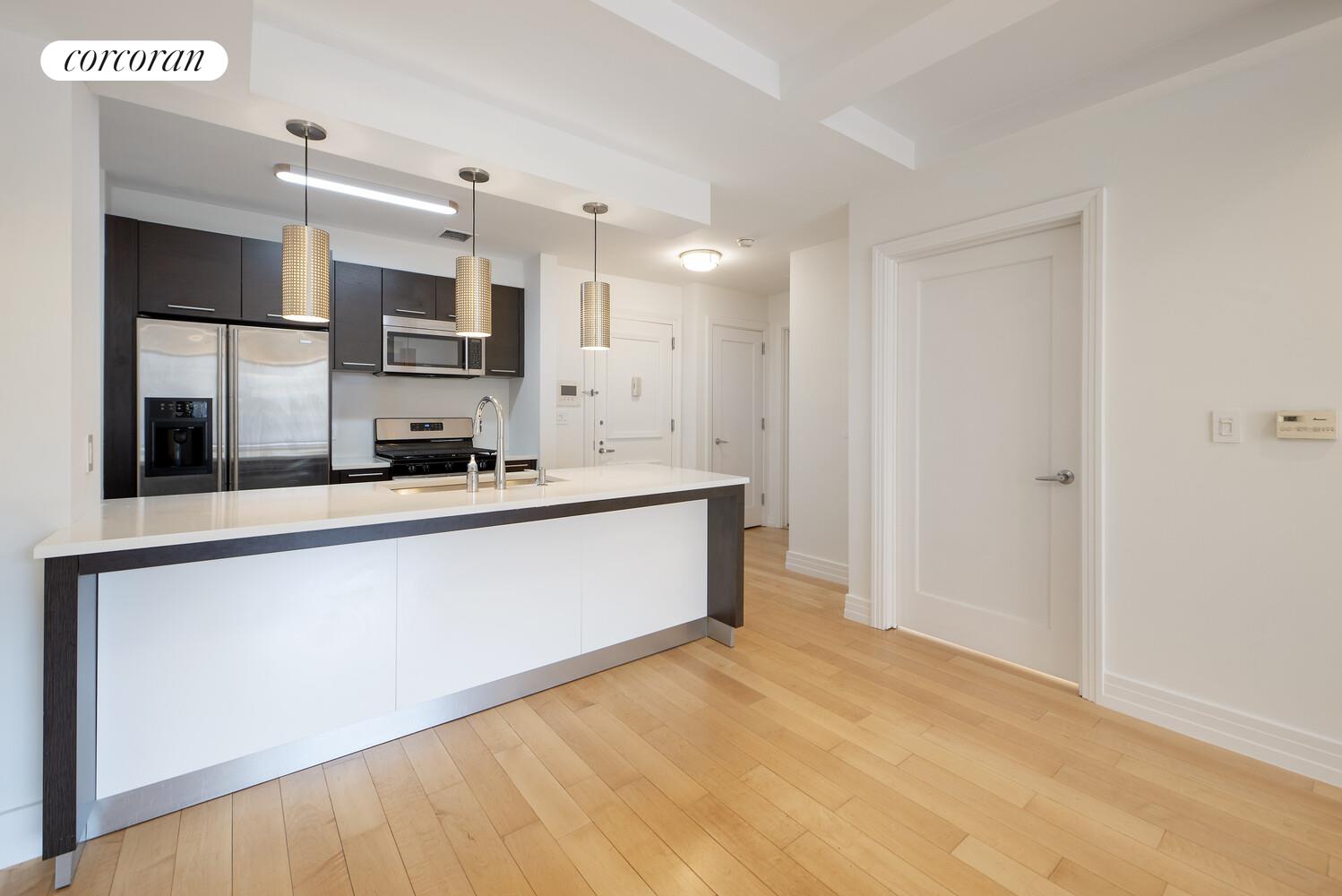 64-05 Yellowstone Boulevard, Unit 213 Queens, NY 11375 - Photo 1 of 15 a large white kitchen with kitchen island a sink stainless steel appliances and cabinets