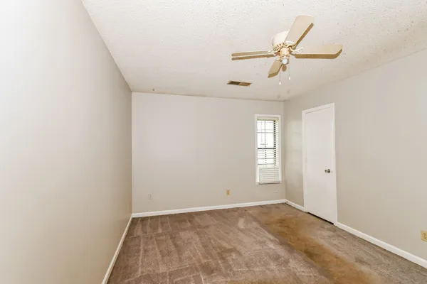 an empty room with windows and fan