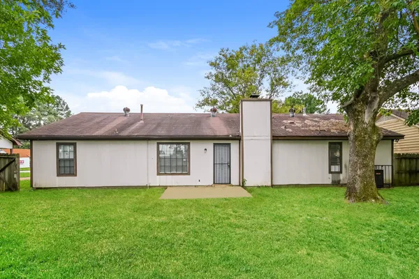 a brick house with potted plants and a large tree