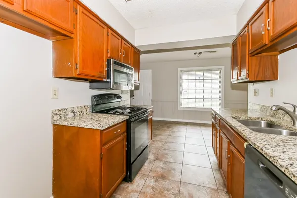 a kitchen with granite countertop a sink a stove and cabinets