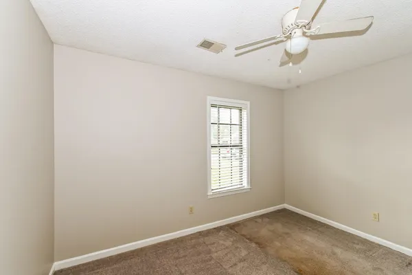 an empty room with windows and fan