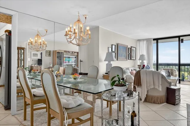 a view of a dining room with furniture a chandelier and large windows