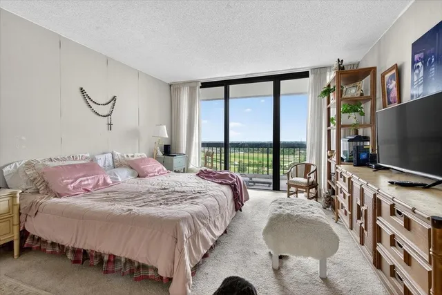 a bedroom with bed and a flat tv screen next to a large window