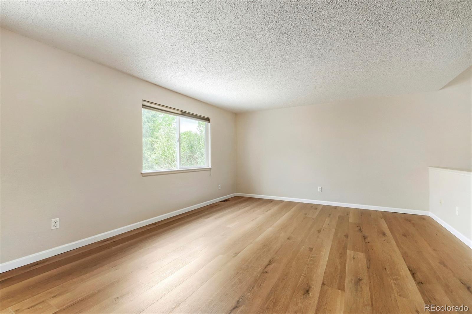 13400 Raritan Street Denver, CO 80234 - Photo 13 of 32 an empty room with wooden floor and windows