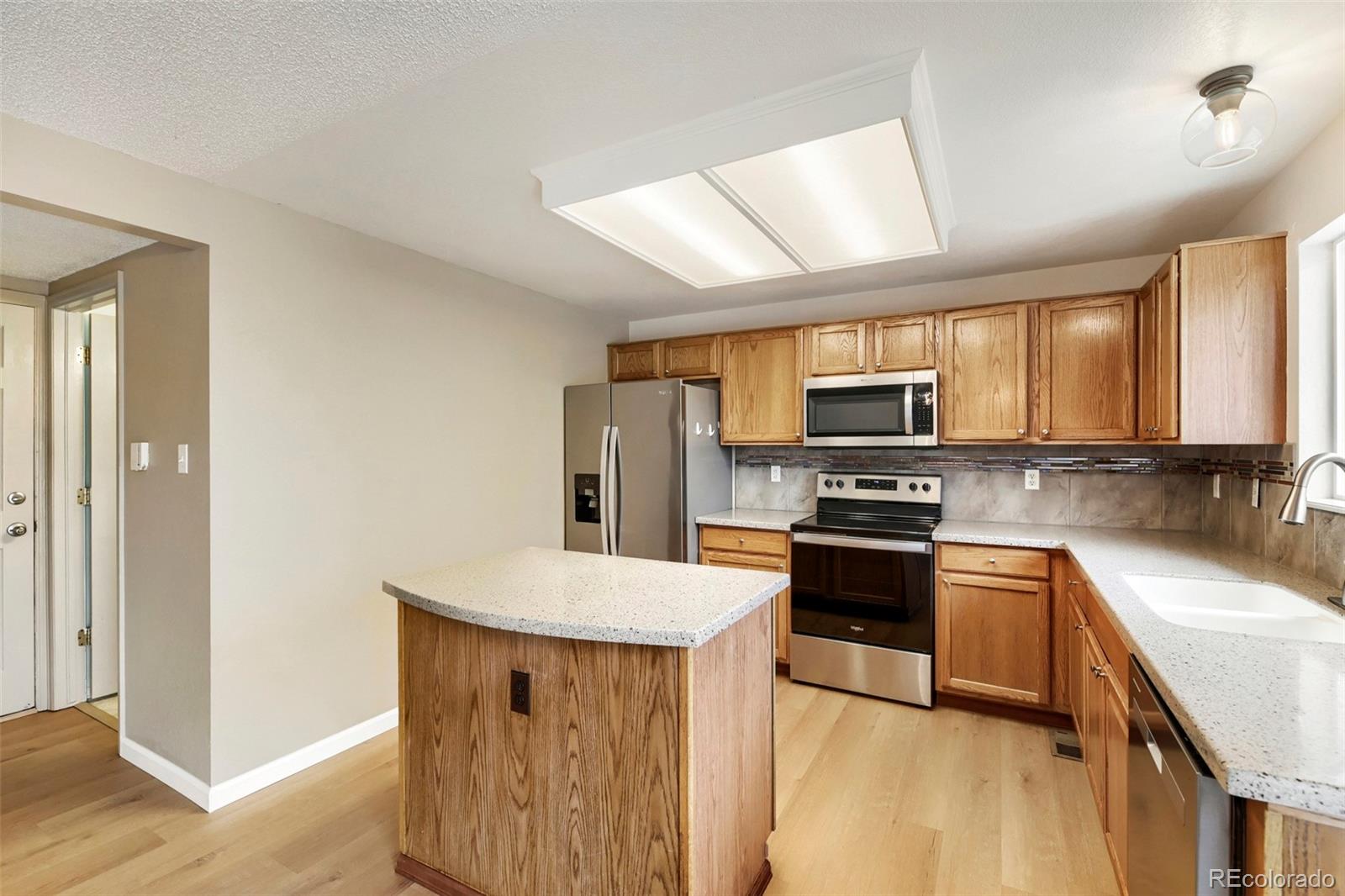 13400 Raritan Street Denver, CO 80234 - Photo 17 of 32 a kitchen with stainless steel appliances granite countertop a sink stove microwave and refrigerator