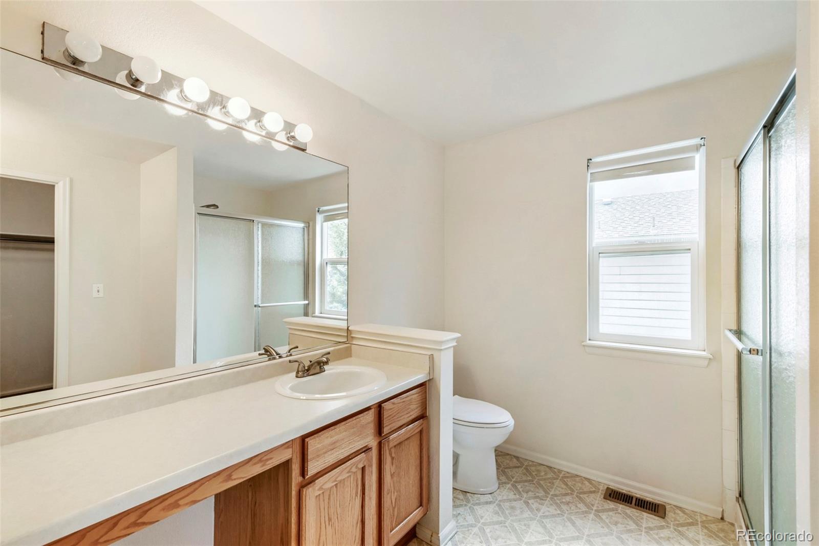 13400 Raritan Street Denver, CO 80234 - Photo 22 of 32 a bathroom with a granite countertop sink a toilet and a mirror