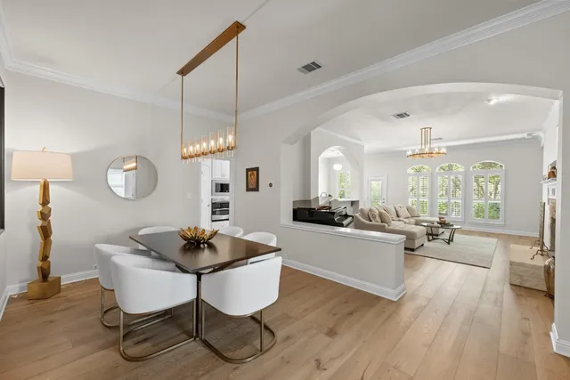 a living room with dining table and couches with wooden floor