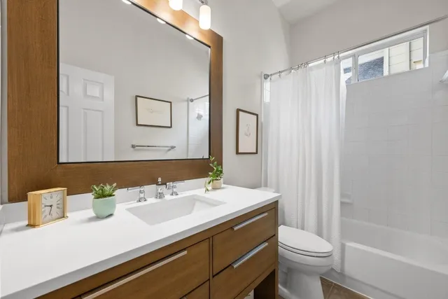 a bathroom with a sink a toilet a mirror and shower