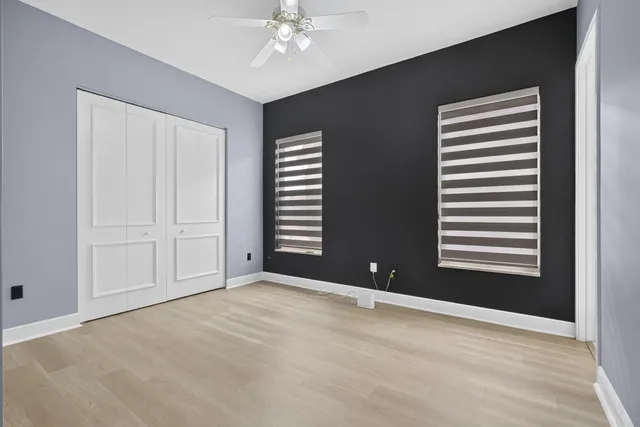 an empty room with a window and ceiling fan