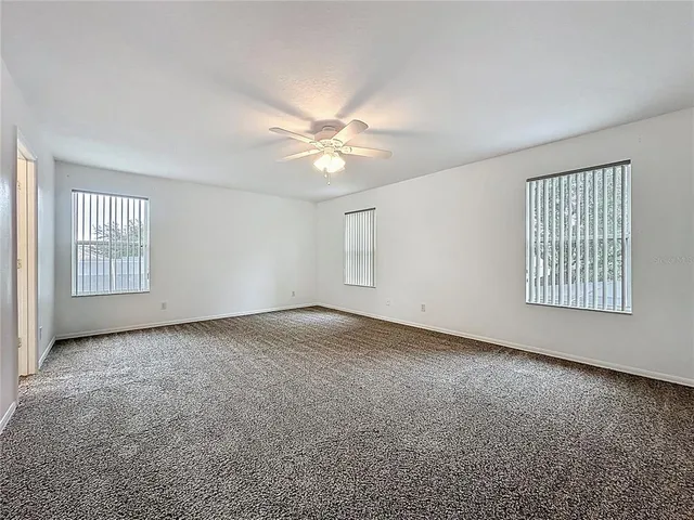 an empty room with windows and ceiling fan