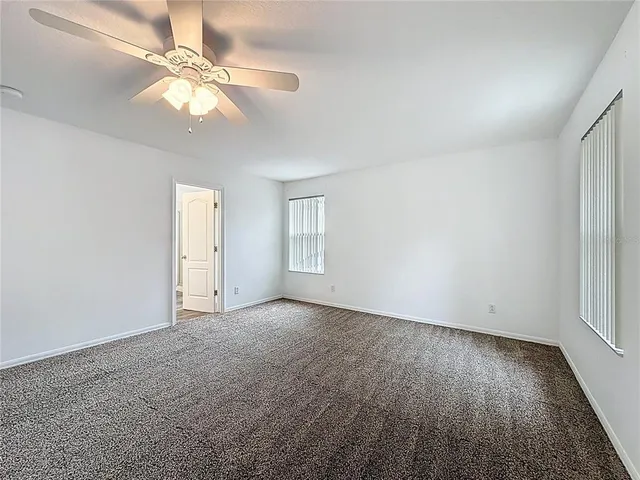 an empty room with wooden floor fan and window