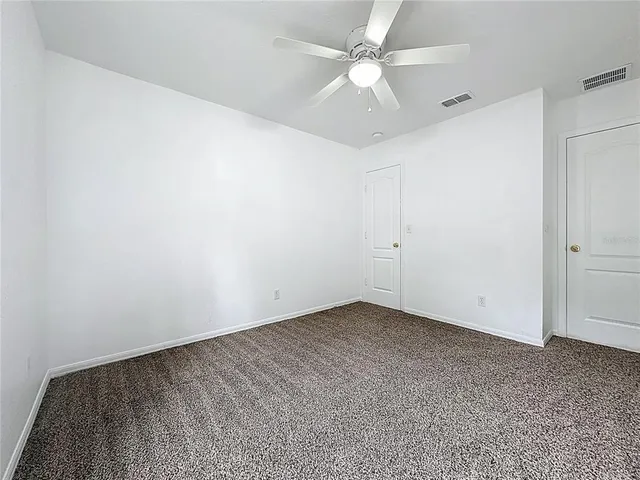 an empty room with a chandelier fan and windows