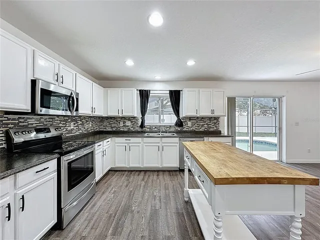 a kitchen with stainless steel appliances granite countertop wooden cabinets a sink dishwasher a stove and a oven