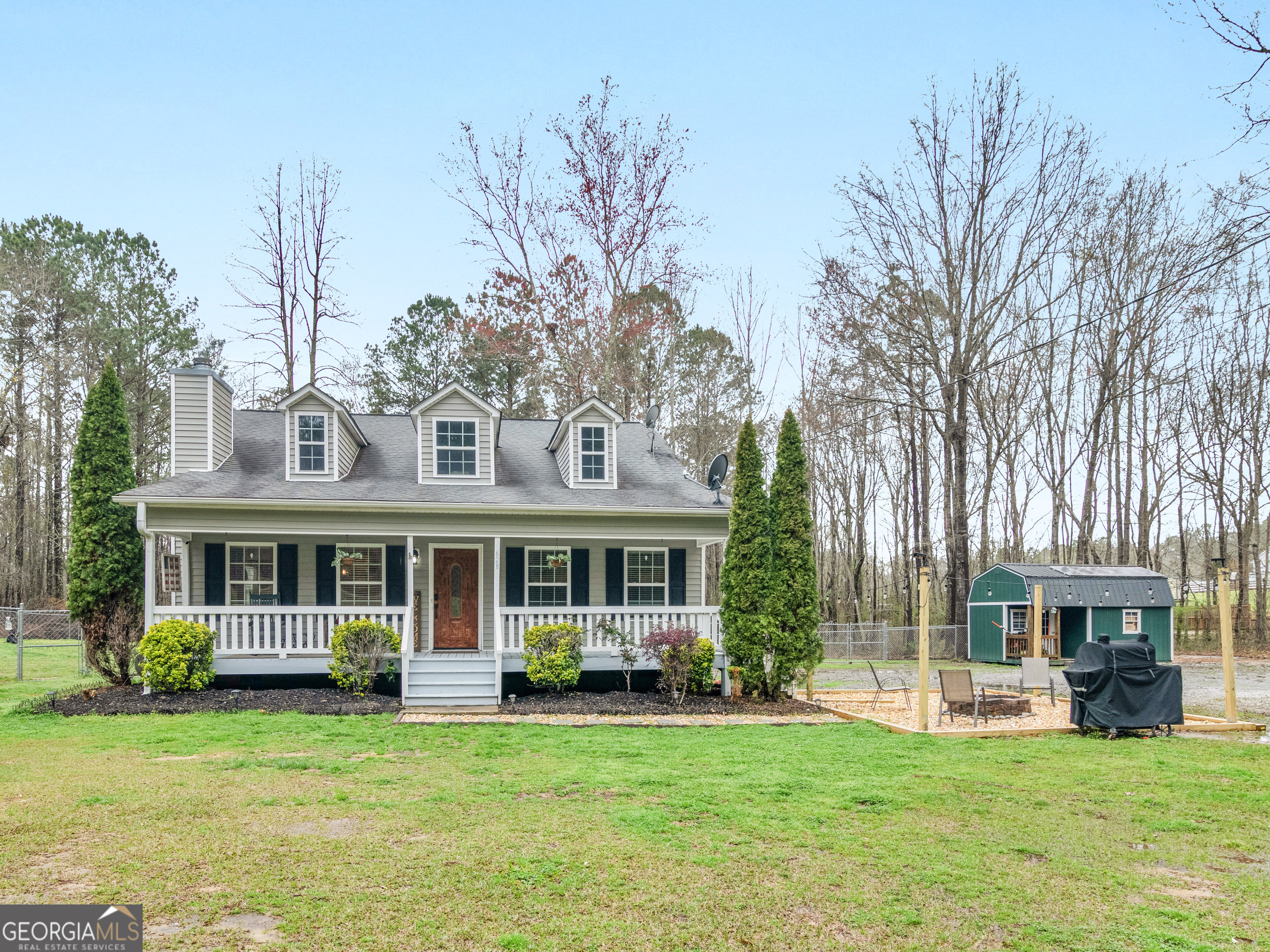 a view of a house with a yard chairs and large trees